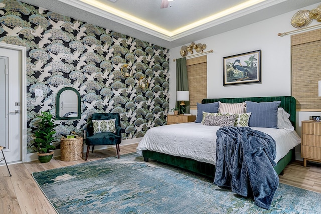 bedroom featuring baseboards, a ceiling fan, wood finished floors, and a raised ceiling