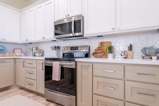 kitchen with decorative backsplash, white cabinetry, appliances with stainless steel finishes, and light hardwood / wood-style flooring