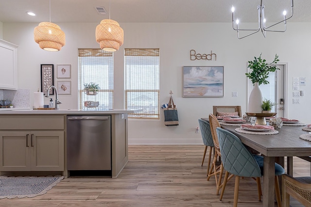 kitchen with white cabinetry, hanging light fixtures, stainless steel dishwasher, light hardwood / wood-style floors, and decorative backsplash