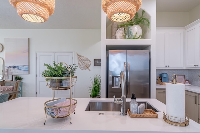 kitchen with white cabinetry, light countertops, stainless steel refrigerator with ice dispenser, and an inviting chandelier