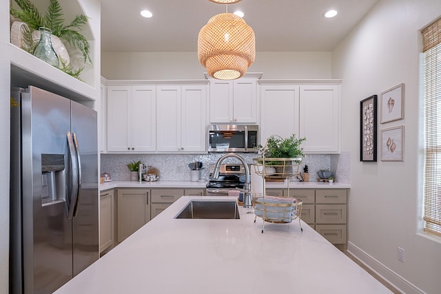 kitchen featuring backsplash, white cabinetry, stainless steel appliances, and decorative light fixtures