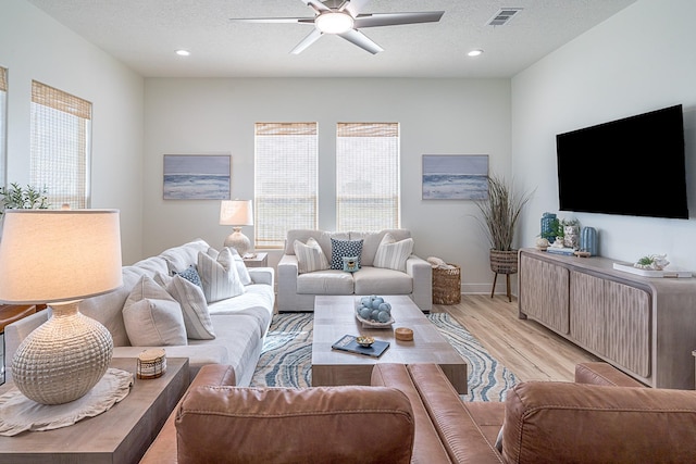 living room featuring ceiling fan, a textured ceiling, and light hardwood / wood-style flooring