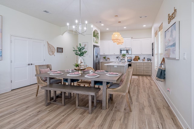 dining area with light hardwood / wood-style floors and a notable chandelier