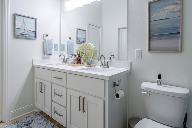 full bathroom featuring double vanity, wood finished floors, toilet, and a sink