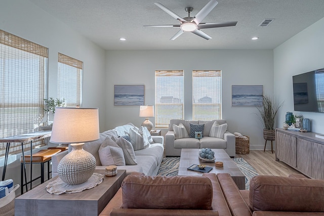 living room featuring a textured ceiling, light hardwood / wood-style flooring, and ceiling fan