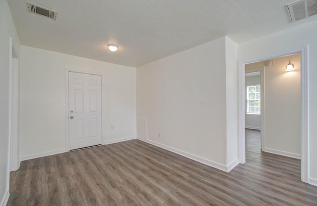 empty room with a textured ceiling and dark hardwood / wood-style floors