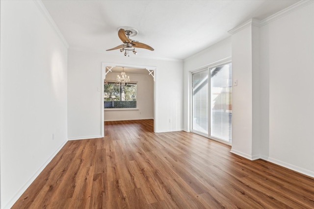 empty room featuring ceiling fan with notable chandelier, hardwood / wood-style floors, and crown molding