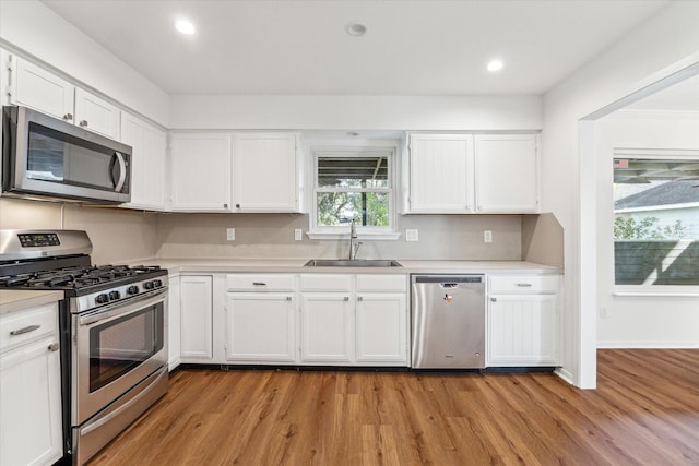 kitchen with white cabinets, sink, stainless steel appliances, and light hardwood / wood-style floors