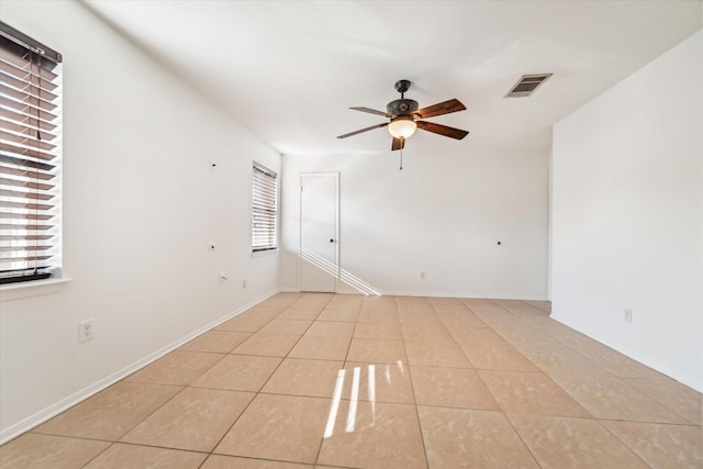 empty room with ceiling fan, a wealth of natural light, and light tile patterned flooring