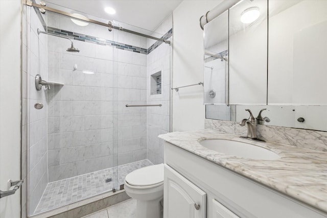 bathroom featuring toilet, vanity, tile patterned floors, and a shower with shower door