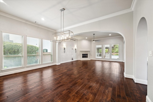 unfurnished living room featuring ceiling fan with notable chandelier, a wealth of natural light, and crown molding