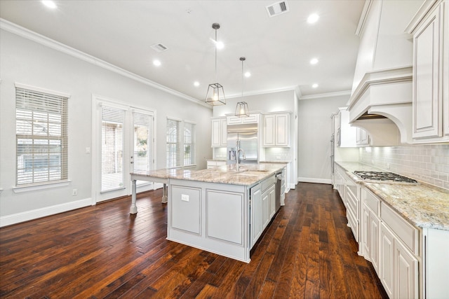 kitchen featuring a center island with sink, decorative light fixtures, white cabinetry, and light stone countertops