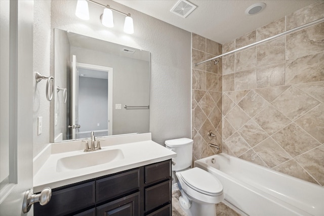 full bathroom with a textured ceiling, vanity, tiled shower / bath combo, and toilet