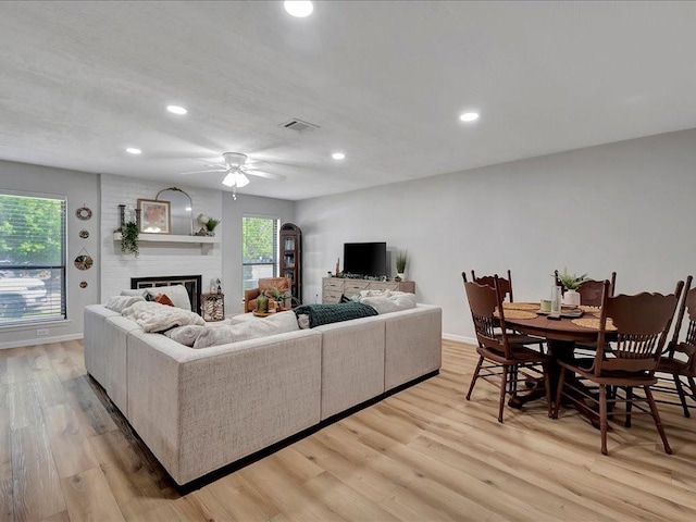 living room with ceiling fan, a fireplace, and light hardwood / wood-style flooring