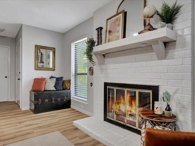 living area featuring wood-type flooring and a brick fireplace