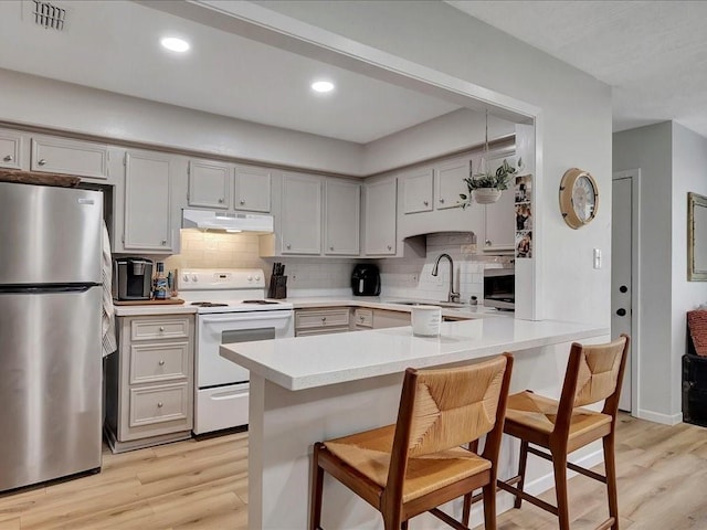 kitchen with a kitchen breakfast bar, light hardwood / wood-style floors, sink, and stainless steel appliances