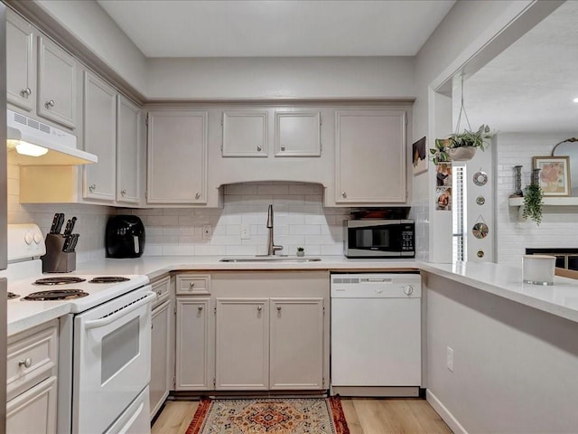 kitchen featuring light hardwood / wood-style floors, white appliances, sink, and tasteful backsplash