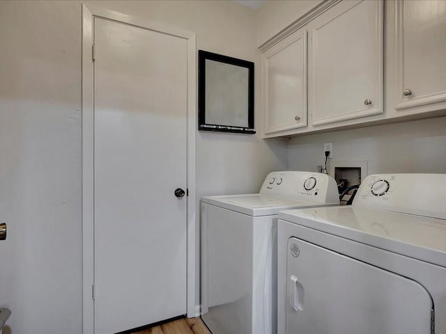 laundry area with washer and dryer, light hardwood / wood-style flooring, and cabinets