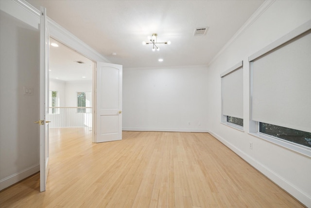 unfurnished room featuring ornamental molding, an inviting chandelier, and light hardwood / wood-style flooring