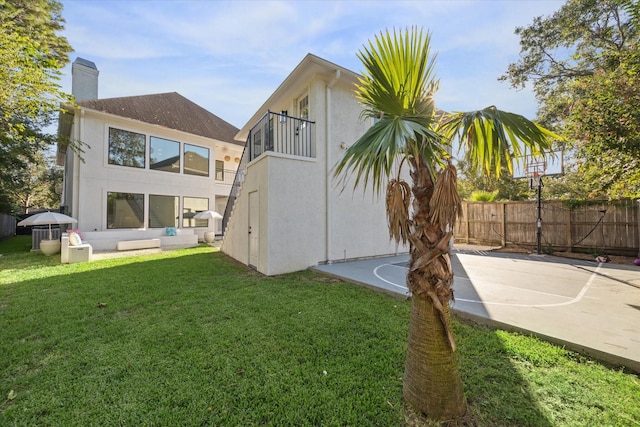 rear view of property featuring a yard and basketball hoop