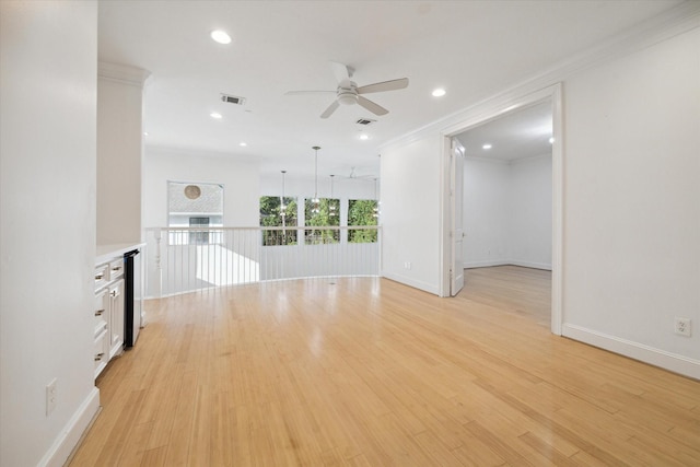 unfurnished living room featuring ornamental molding, ceiling fan, and light hardwood / wood-style flooring