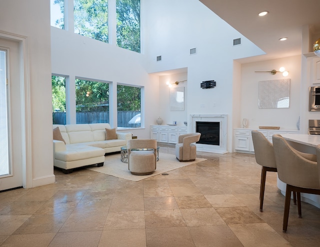 living area with a towering ceiling, visible vents, and a premium fireplace