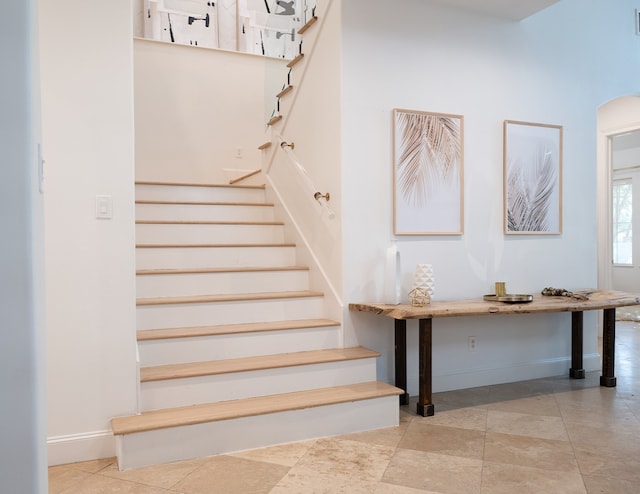 staircase featuring a high ceiling and baseboards