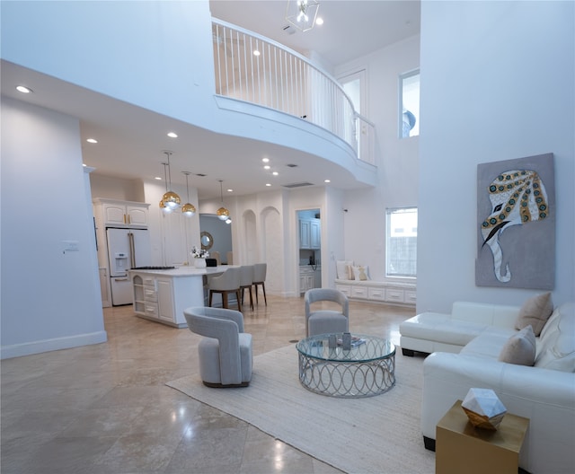 living room featuring a towering ceiling, a healthy amount of sunlight, and a notable chandelier