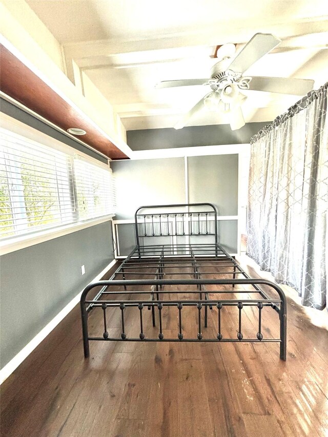 bedroom with wood-type flooring, ceiling fan, and beam ceiling