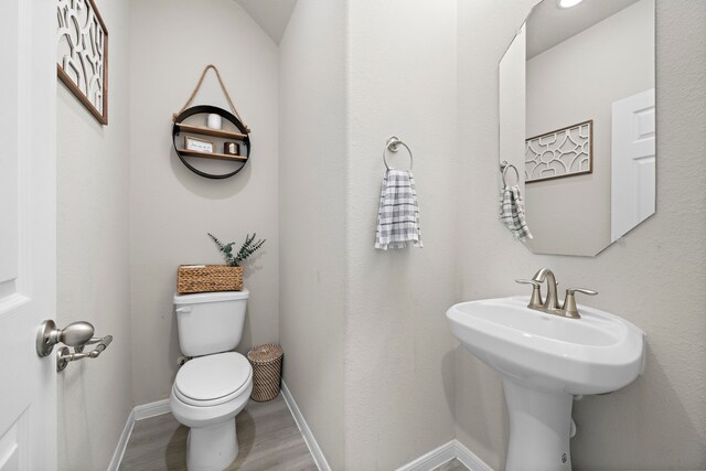 bathroom featuring wood-type flooring and toilet