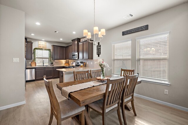 dining room with an inviting chandelier, light hardwood / wood-style flooring, and sink