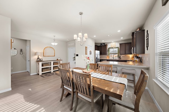 dining space with sink, light hardwood / wood-style flooring, a wealth of natural light, and a chandelier