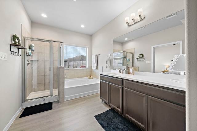 bathroom with hardwood / wood-style floors, vanity, and shower with separate bathtub