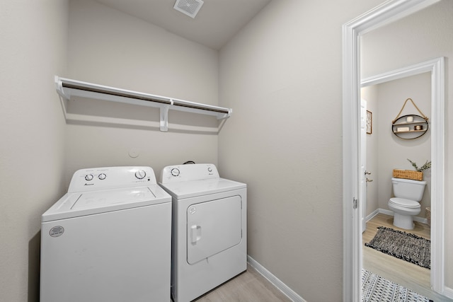 clothes washing area with washer and dryer and light hardwood / wood-style floors