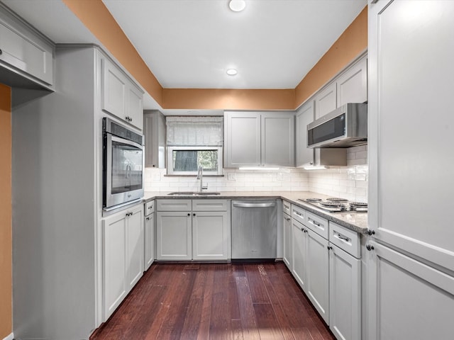 kitchen with dark wood-type flooring, sink, decorative backsplash, light stone countertops, and stainless steel appliances