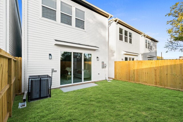 back of property with a lawn and central AC unit