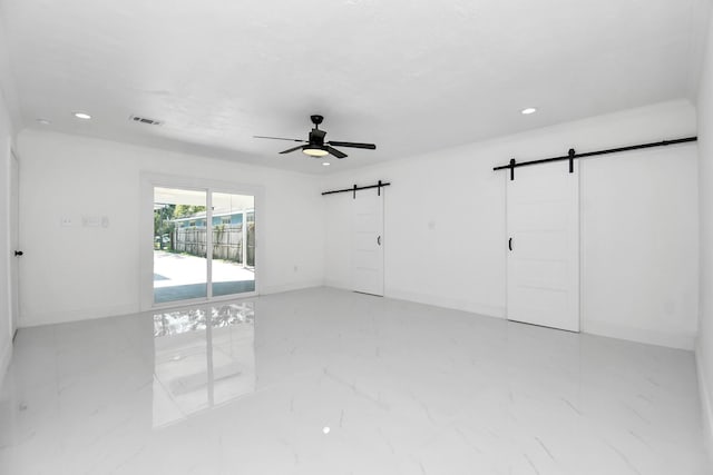 unfurnished room with ceiling fan and a barn door