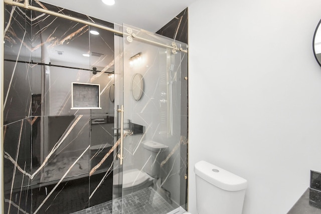 bathroom featuring toilet and a shower with shower door