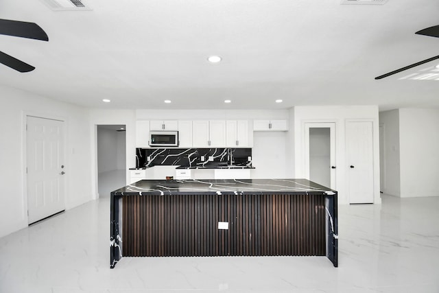 kitchen with backsplash, a center island, and white cabinets