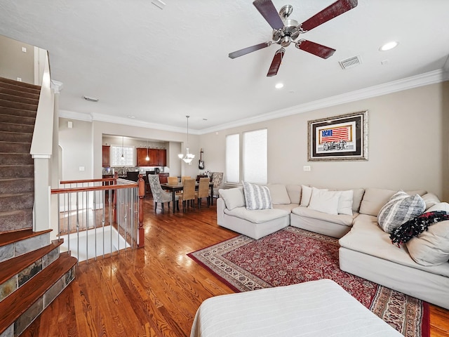 living room with hardwood / wood-style floors, ceiling fan with notable chandelier, and crown molding