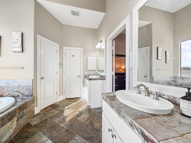 bathroom featuring tiled tub, a towering ceiling, and vanity