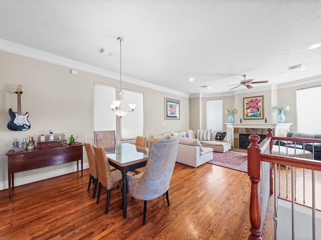 dining space with hardwood / wood-style floors, ceiling fan with notable chandelier, and crown molding