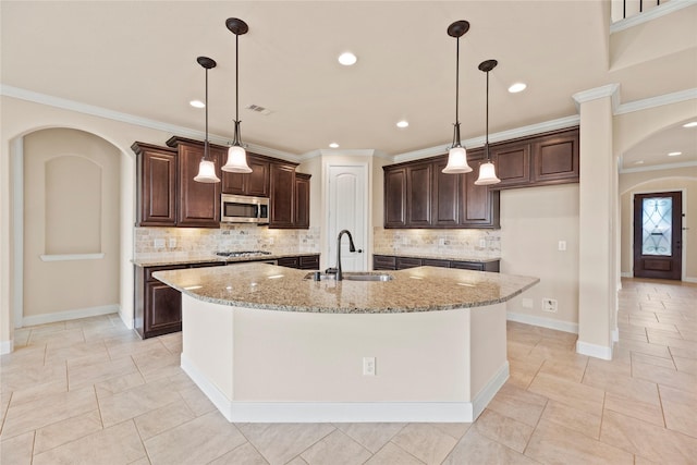 kitchen with a kitchen island with sink, sink, stainless steel appliances, and light stone counters