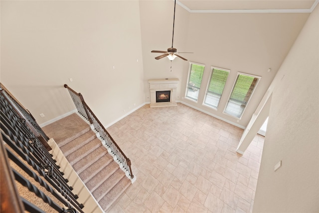 unfurnished living room with ceiling fan, a high ceiling, and ornamental molding