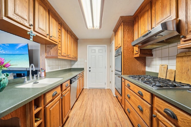 kitchen with tasteful backsplash, sink, light wood-type flooring, and appliances with stainless steel finishes