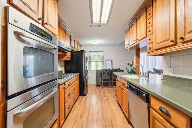 kitchen featuring light hardwood / wood-style floors, sink, stainless steel appliances, and tasteful backsplash