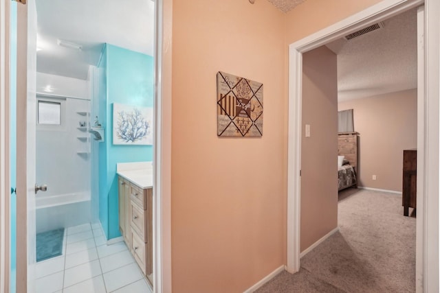 corridor featuring a textured ceiling and light colored carpet