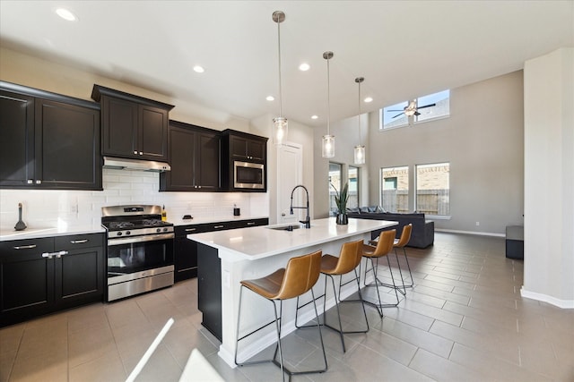 kitchen with sink, light tile patterned floors, stainless steel appliances, and an island with sink