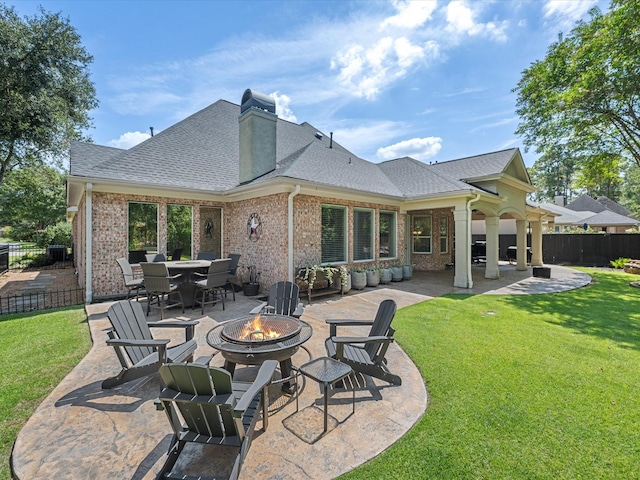 back of property with a yard, an outdoor fire pit, and a patio