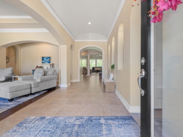 foyer entrance with light tile patterned floors, vaulted ceiling, and ornamental molding